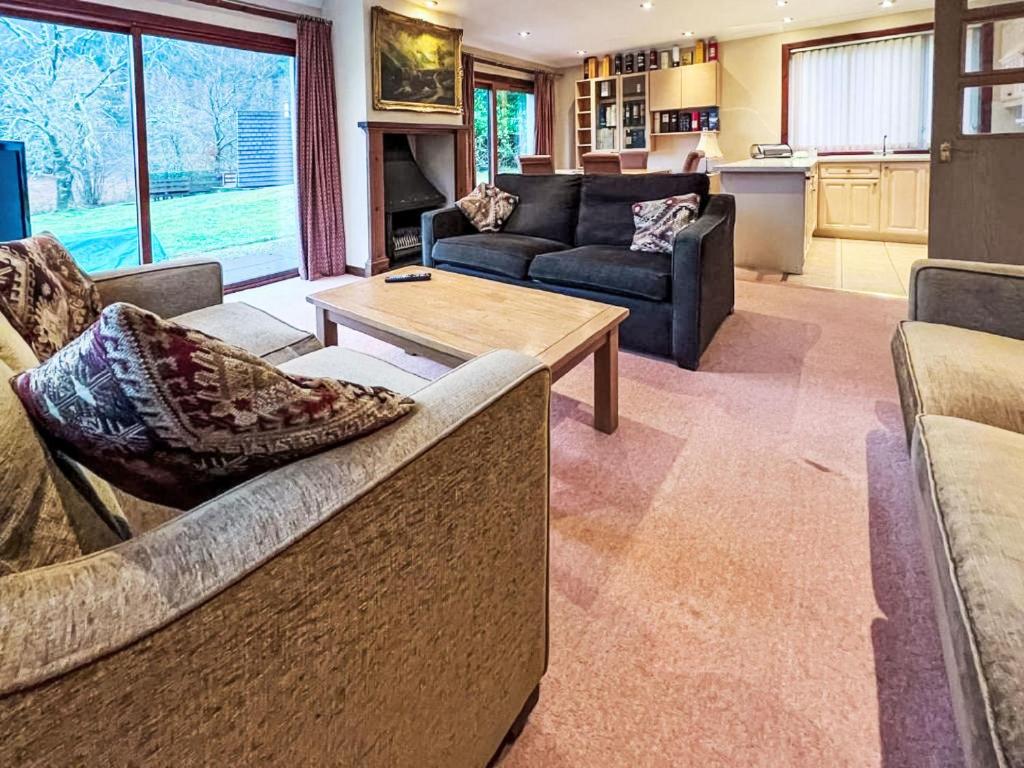 a living room with couches and a table and a kitchen at Chalet Glen View by Interhome in Spean Bridge