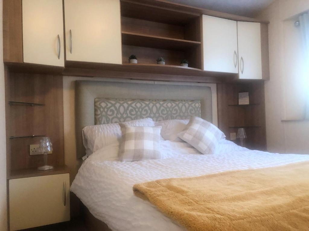 a bedroom with a bed with white sheets and cabinets at Rivington Retreat in Heysham