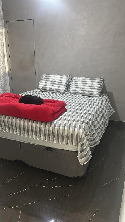 uma cama com um cobertor vermelho e almofadas em Casa para Agrishow 5min em Ribeirão Preto