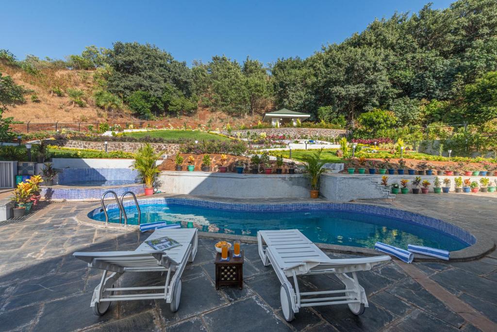 a swimming pool with two chairs and a table at SaffronStays Caramelo - a private swimming pool villa nestled amidst beautiful landscaping and gardens in Lavasa in Lavasa