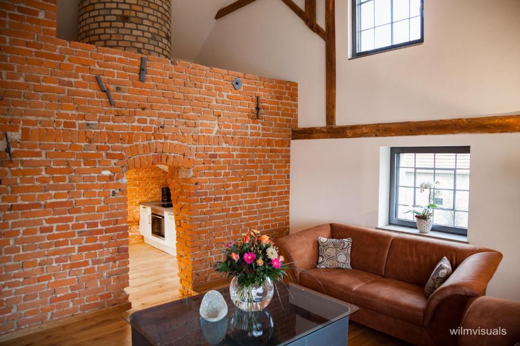 un salon avec un canapé et un mur de briques dans l'établissement Ferienwohnungen - Alte Brauerei, à Rauhenebrach