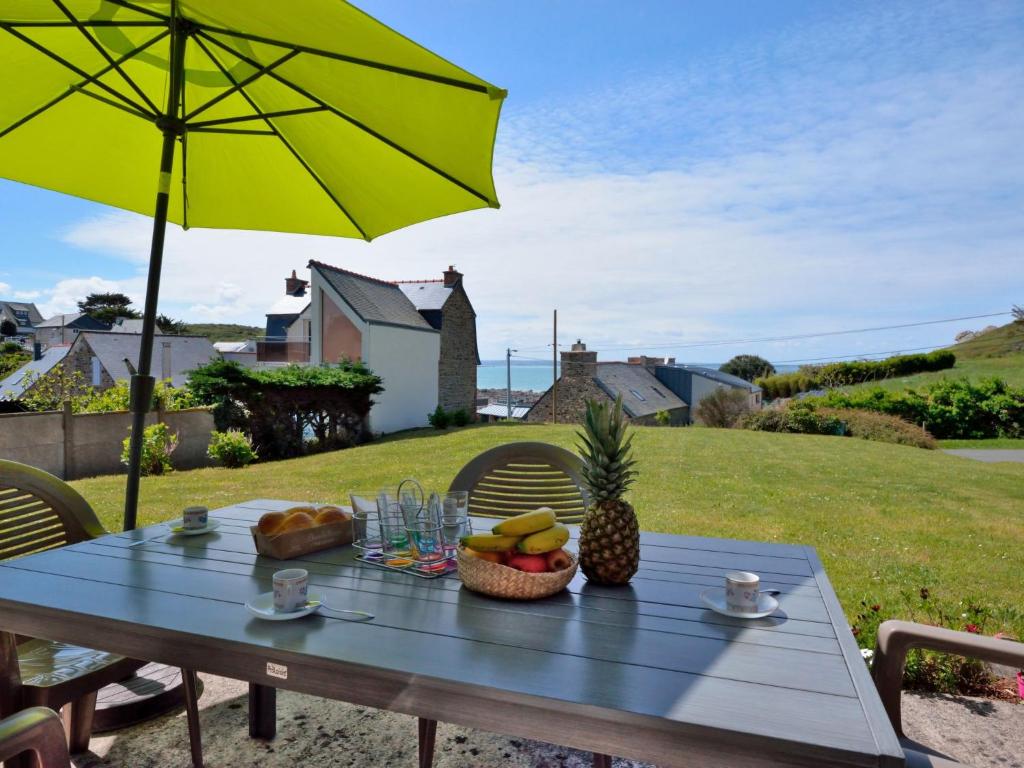 ein Picknicktisch mit einem Regenschirm und Obst darauf in der Unterkunft Holiday Home Port Morvan by Interhome in Planguenoual