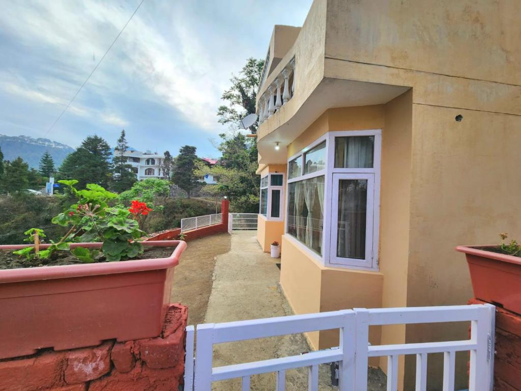 a building with a white fence and some plants at Villa Kartina by the Hillstay in Bhowāli