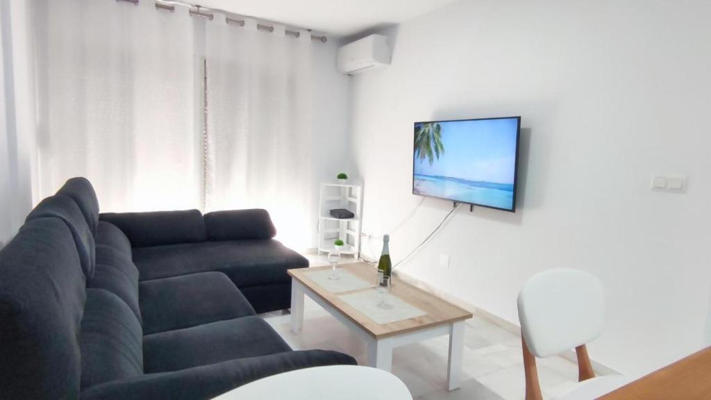 sala de estar con sofá y TV en la pared en Fantástico apartamento totalmente renovado, en Torre del Mar