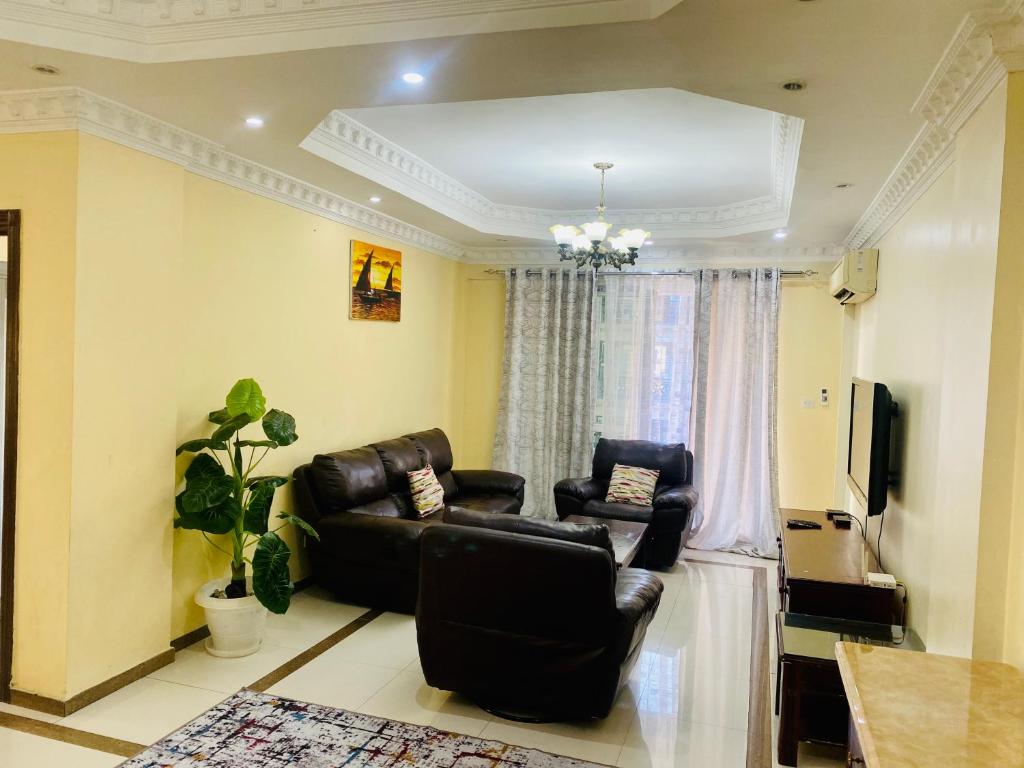 Platinum apartment في دار السلام: غرفة معيشة مع كرسيين جلديين وتلفزيون