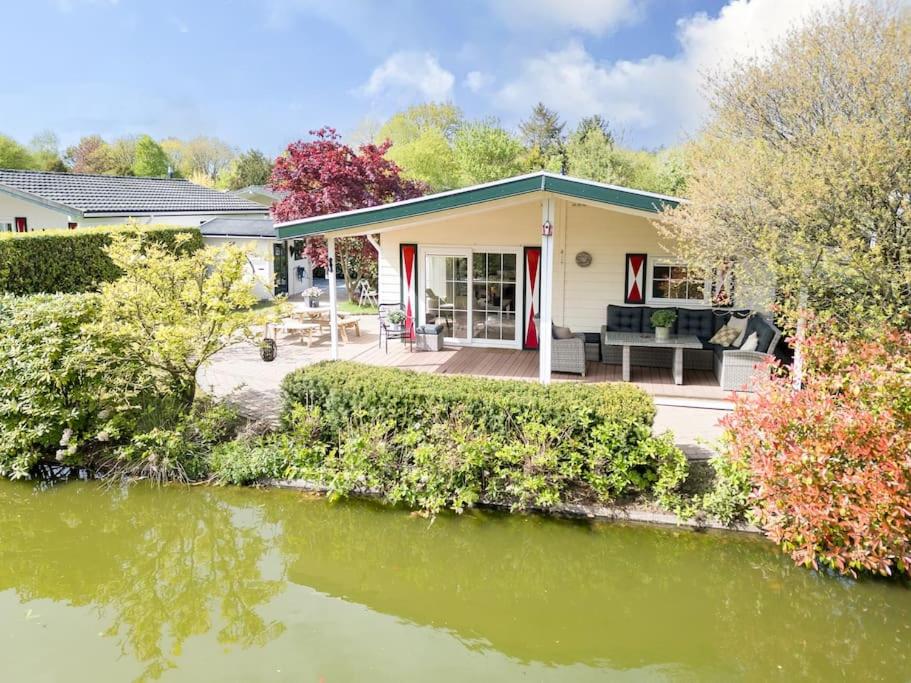 a house with a pond in front of it at Prachtige vakantiewoning aan water met grote tuin in Voorthuizen
