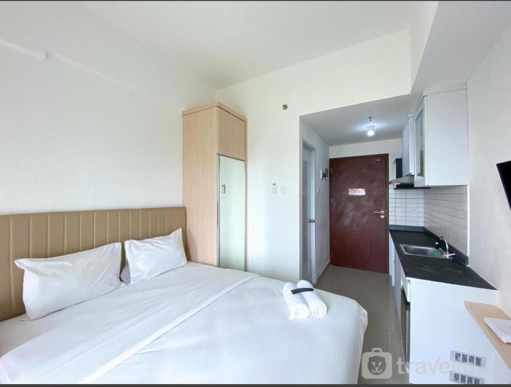 a bedroom with a white bed and a sink at Capital O 93854 Apartemen Sayana By Sentra Jaya in Bekasi