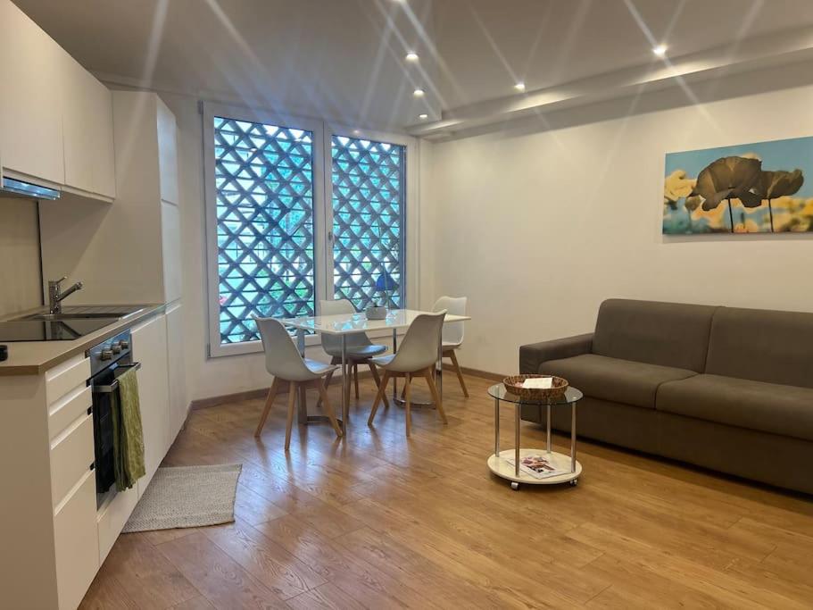Una sala de estar con un sofá, una mesa y sillas. en Palm Beach apartment Bissone, en Bissone