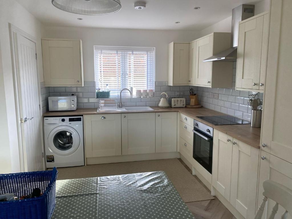 a kitchen with white cabinets and a washing machine at Bluebells, Little Snoring in Fakenham