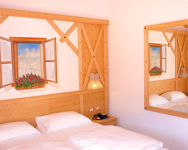 a bedroom with two beds and two windows at B&B Longanorbait in Folgaria