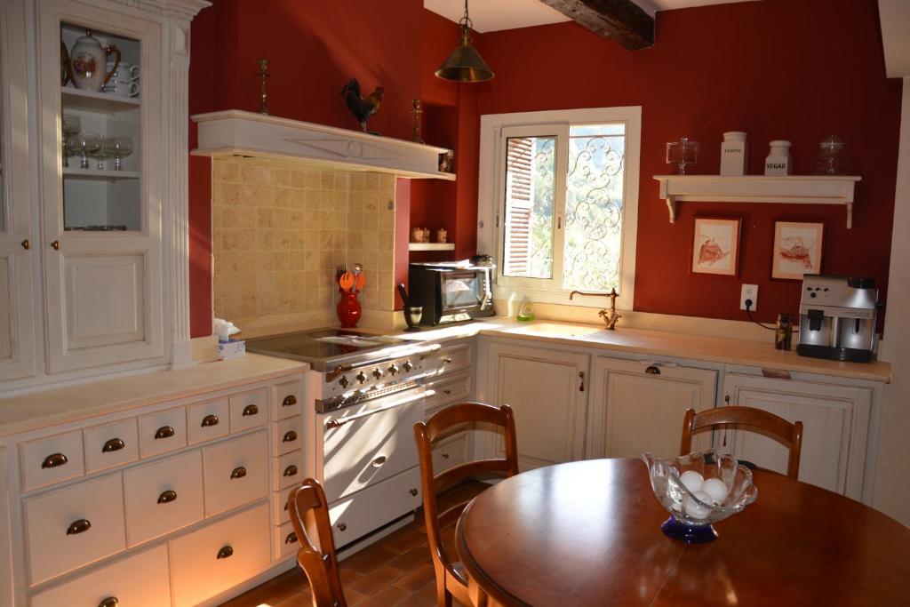 una cucina con pareti rosse, tavolo in legno, tavolo e sala da pranzo di La Maison Vieille a Peillon