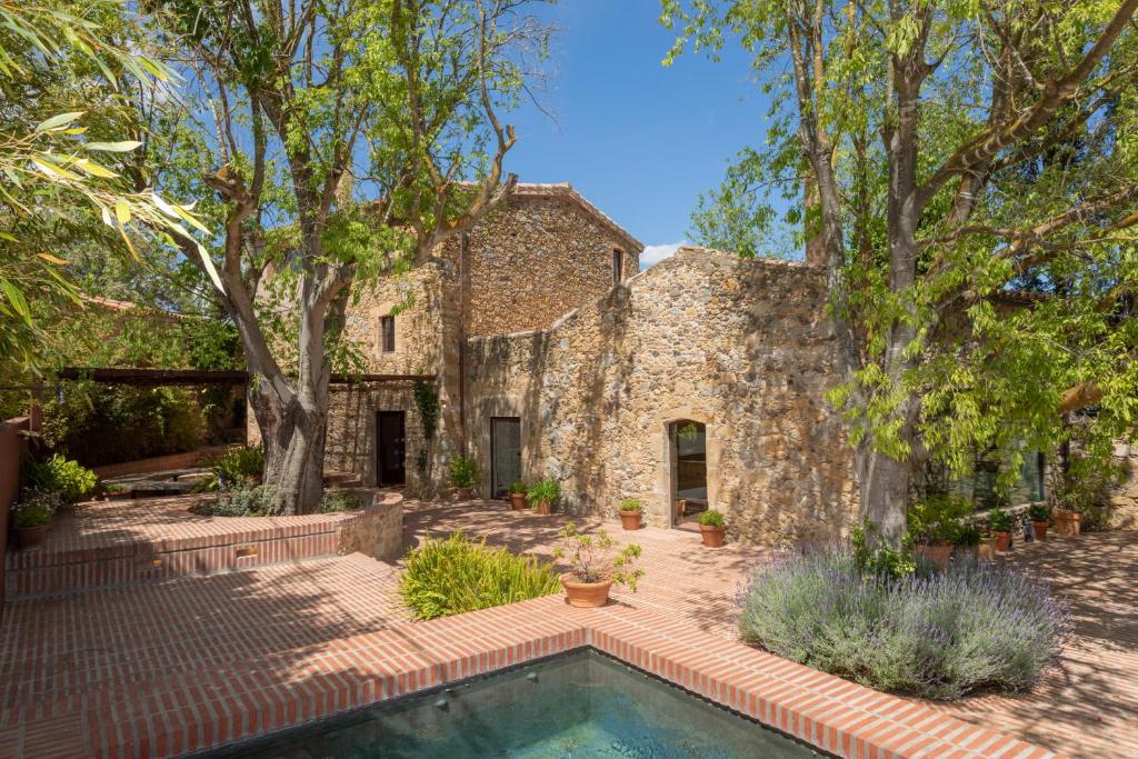 Casa de piedra antigua con piscina y árboles en Flateli Corçà, en Corçà