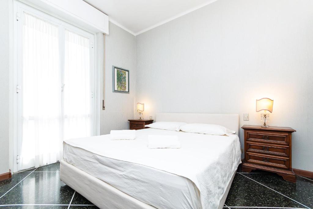 a white bedroom with a large bed and a window at IMMOBIRENT - 5min spiagge - 15min centro città in Genoa