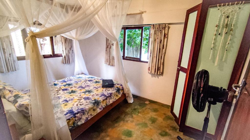 1 dormitorio con 1 cama con cortinas y ventana en Kitesurf Tofo House en Praia do Tofo