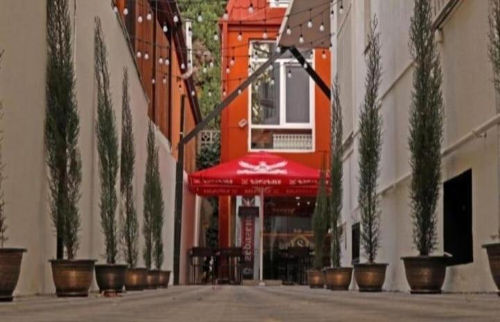 een lege straat met potplanten en een rode paraplu bij Семейный отель in Tbilisi City
