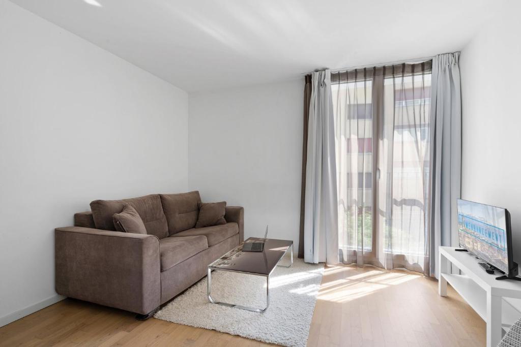 een woonkamer met een bank en een tv bij Boissonnet 96 Residence by Homenhancement in Lausanne