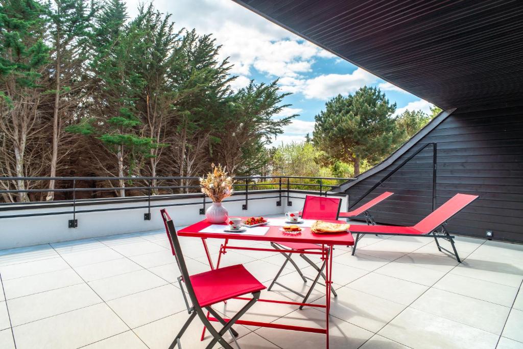 d'une terrasse sur le toit avec une table rouge et des chaises. dans l'établissement Ty Kenlou du Cabellou - Appartement sur la plage, à Concarneau