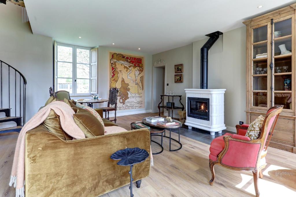 ein Wohnzimmer mit einem Sofa und einem Kamin in der Unterkunft La petite châtelaine - Charmante maison au calme 