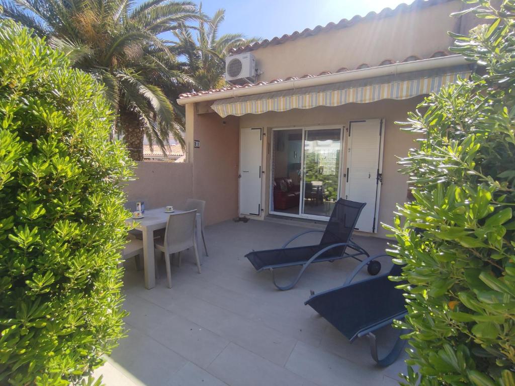 un patio avec une table et des chaises devant une maison dans l'établissement Villa 21, Cap Sauvage au village naturiste, au Cap d'Agde