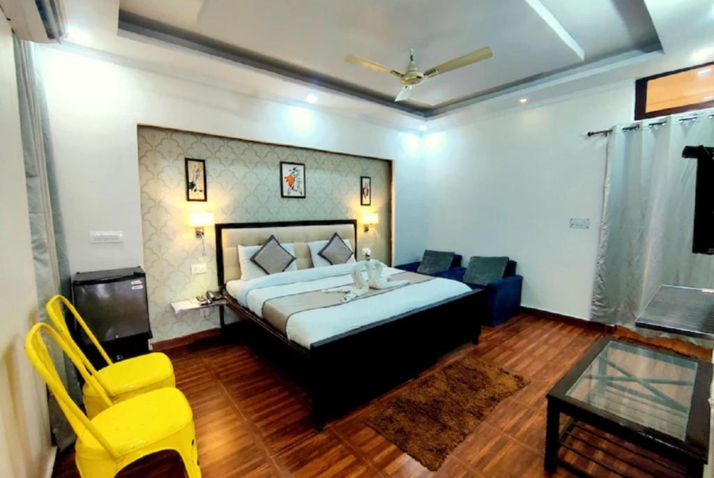 a bedroom with a bed and a table and yellow chairs at Hotel Krishna Residency Bareilly Near Ashish Royal Park in Bareilly