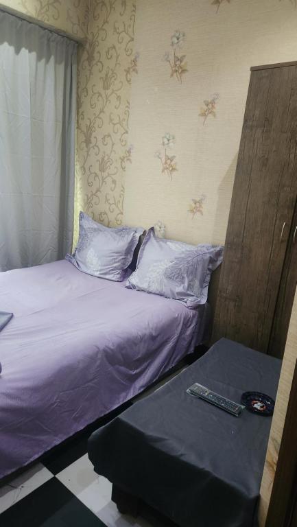 a bed with purple sheets and a remote control on it at Formula1 in Tbilisi City