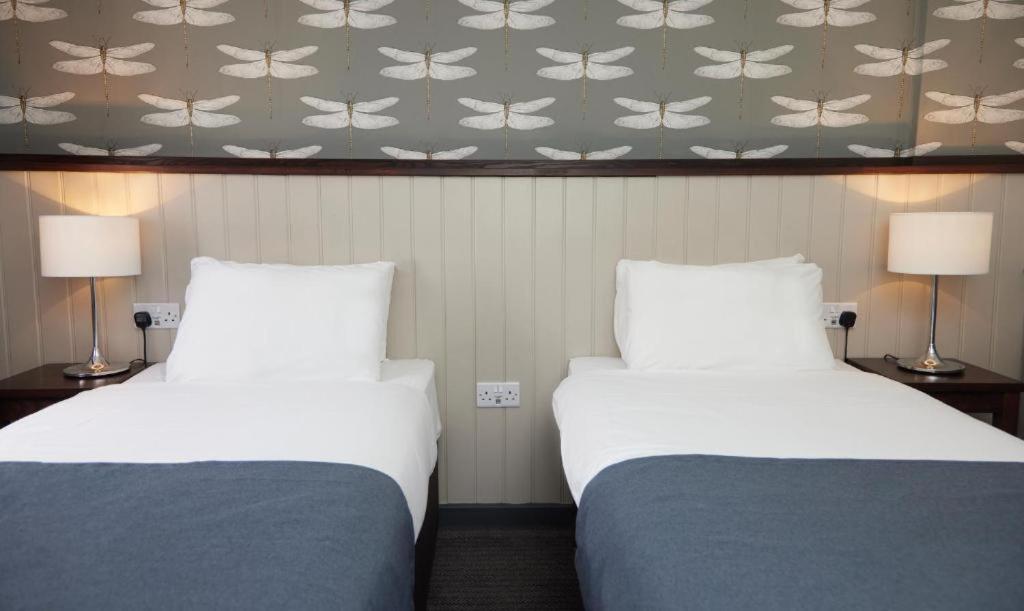 a hotel room with two beds and a wallpaper with butterflies at Charnwood Arms in Coalville