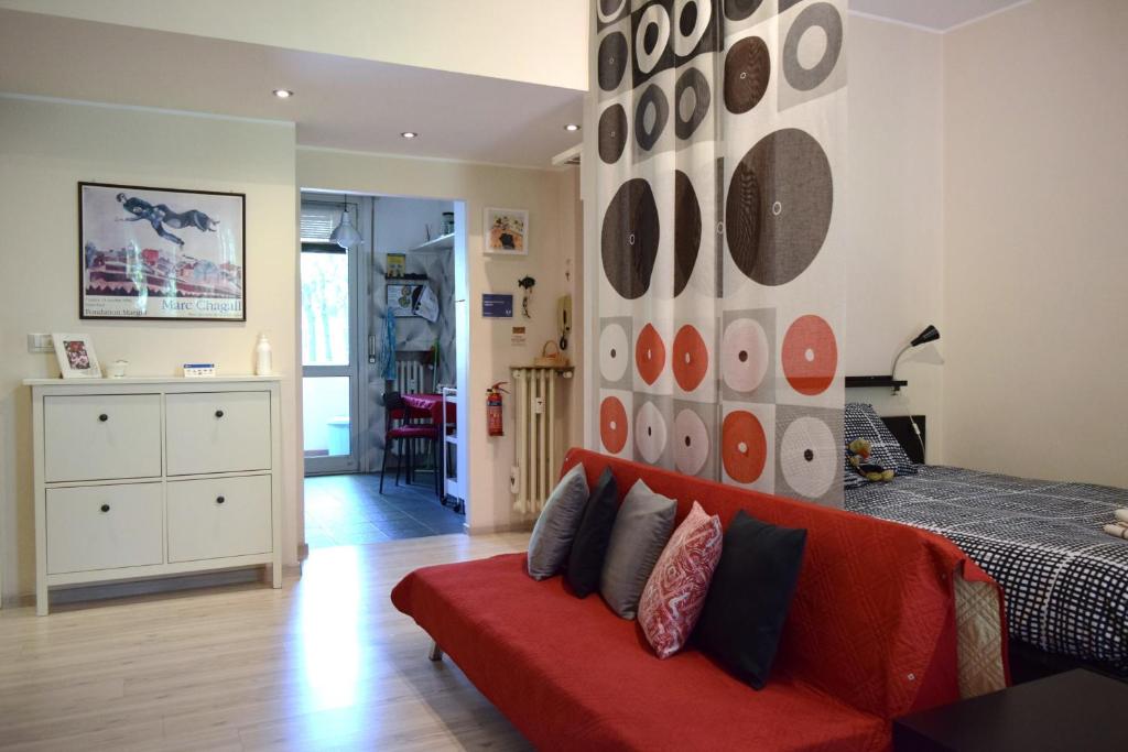 - un salon avec un canapé rouge et un mur avec des disques dans l'établissement Casa Laghetto San Donato Policlinico, à San Donato Milanese