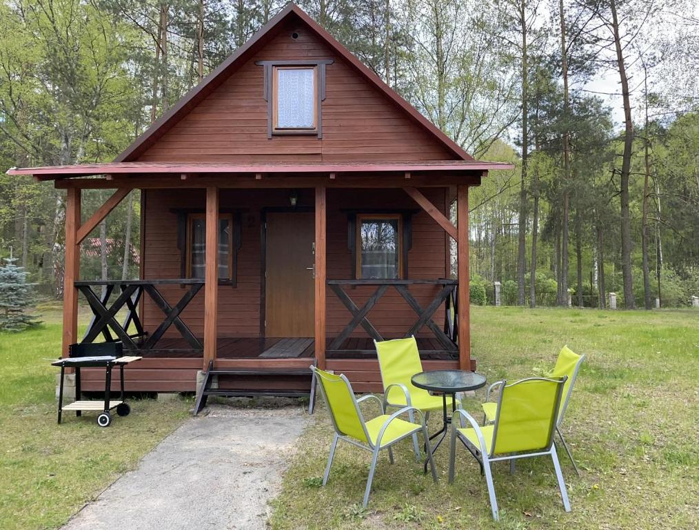 a small cabin with chairs and a table in front of it at Domki Letniskowe Nad Jeziorem Kazub in Cieciorka
