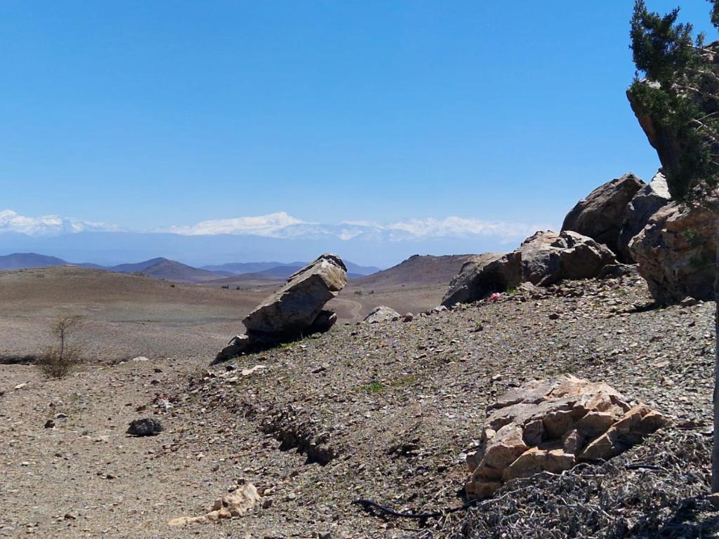 un grupo de rocas en una colina con montañas en el fondo en Noé Nomade, en Sidi Bou Othmane