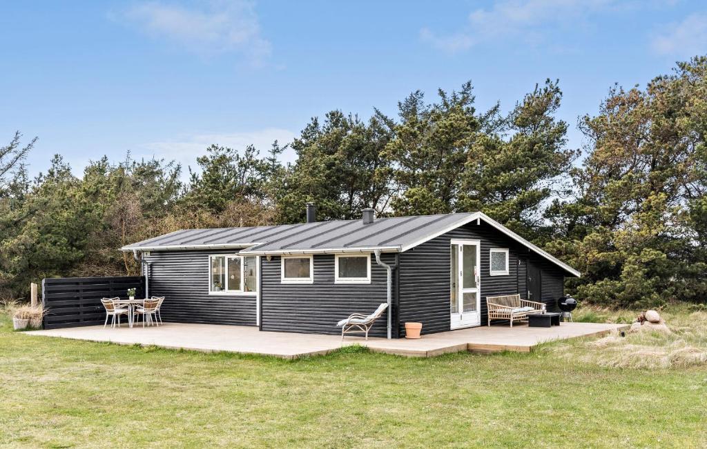a black tiny house with a deck in a field at Awesome Home In Hirtshals With Kitchen in Hirtshals