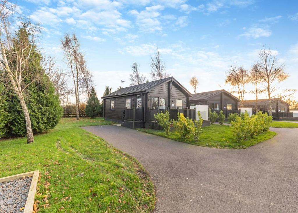 a black house with a driveway in front of it at Snainton Luxury Lodges in Ebberston