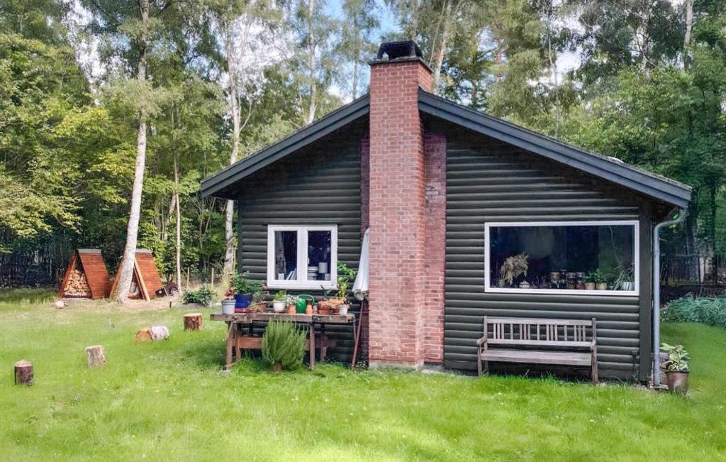 une petite maison avec un banc dans l'herbe dans l'établissement 3 Bedroom Awesome Home In Frederiksvrk, à Frederiksværk