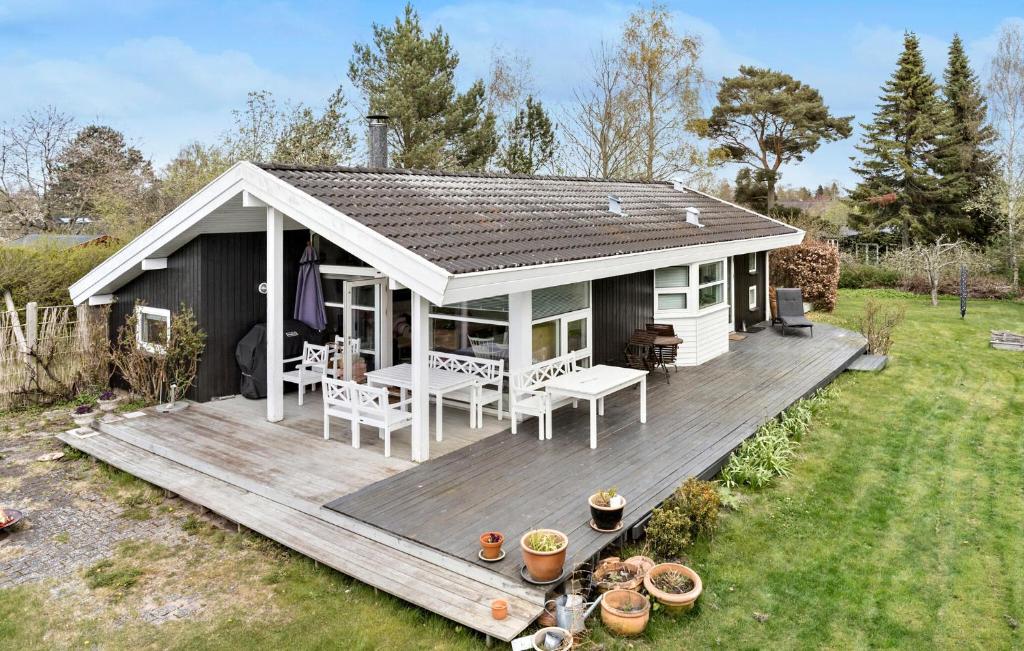 a small white house with a wooden deck at Stunning Home In Dronningmlle With Wifi in Dronningmølle
