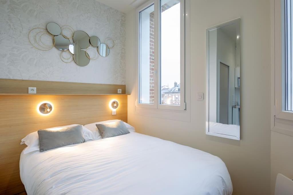 une chambre avec un grand lit blanc avec deux oreillers dans l'établissement Appartement 2 proche de la gare et centre ville, à Amiens