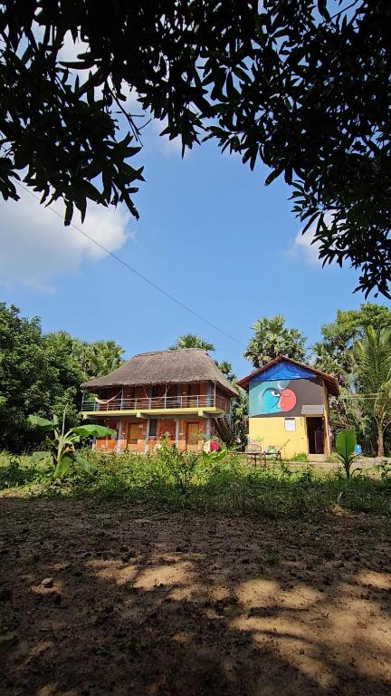 a house with a thatched roof in front at Time Travellers Farm Stay in Auroville
