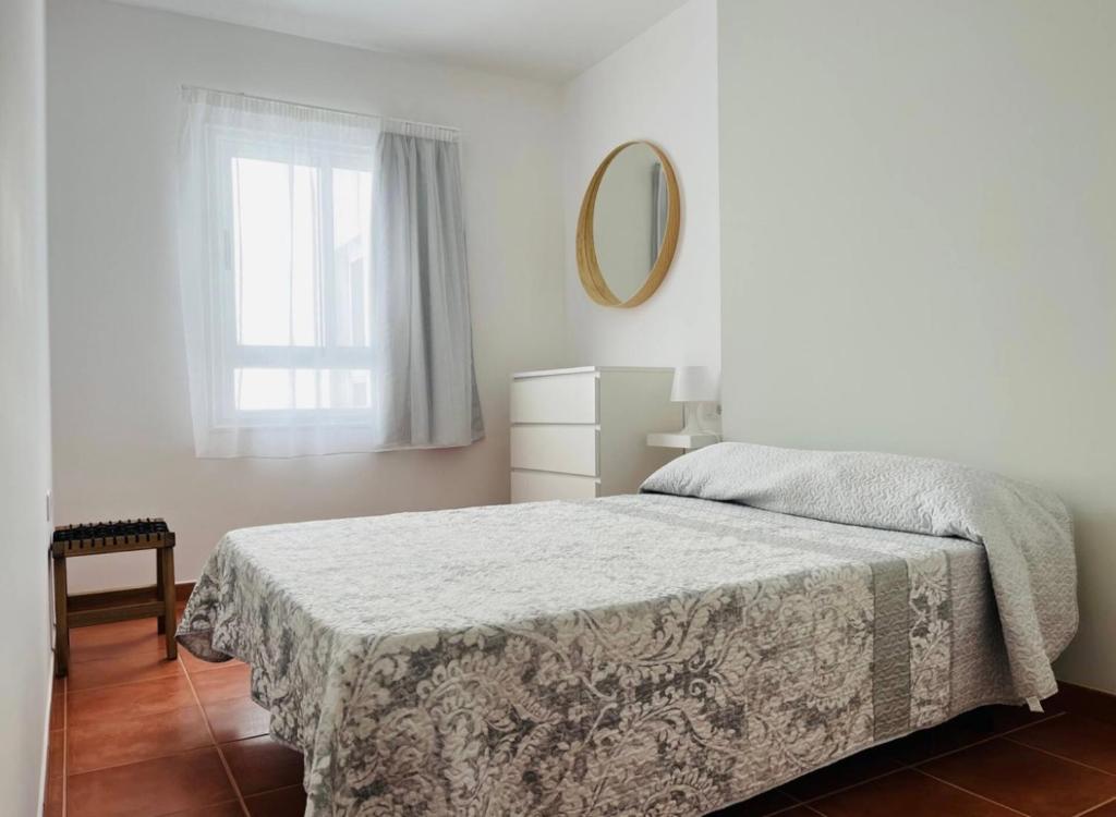 Habitación blanca con cama y espejo en Apartamento Ophelia, en Puerto del Rosario