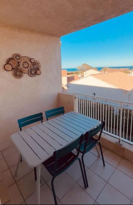une table bleue et deux chaises sur un balcon avec une table et une fenêtre dans l'établissement Charmant T2 rénové avec vue mer, à Cervione