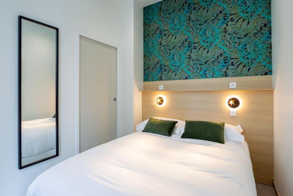 - une chambre avec un lit blanc et 2 oreillers verts dans l'établissement Appartement 1 proche de la gare et du centre ville, à Amiens