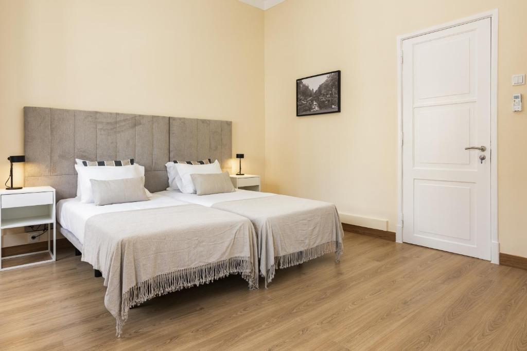 een slaapkamer met een groot bed met witte lakens bij City Rooms - Amesterdao - Private room by HD in Faro
