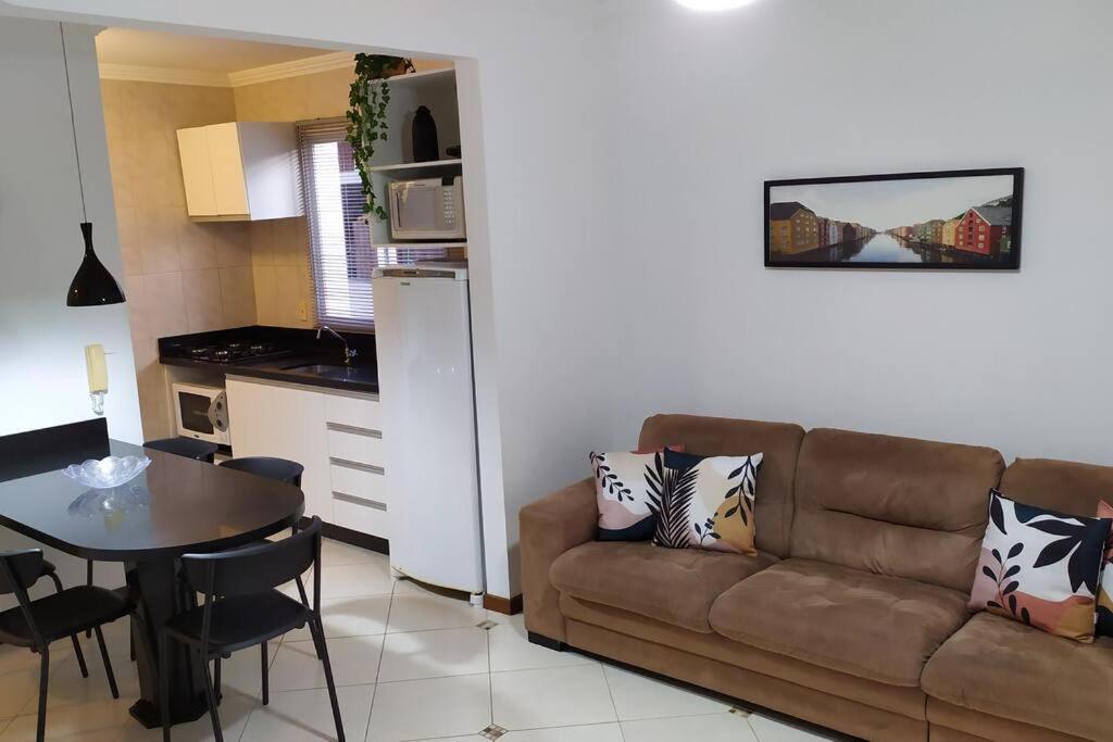 a living room with a couch and a table and a kitchen at Apartamento 102 do Residencial Argonauta in Bombinhas