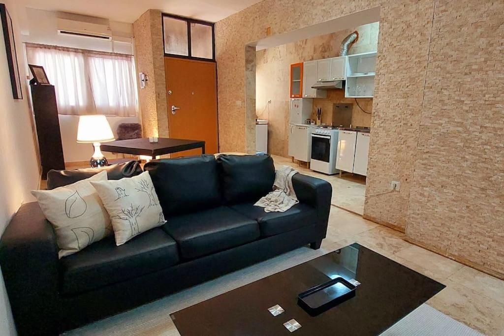 uma sala de estar com um sofá preto e uma mesa em Moody & cozy 1br in city center em Luanda