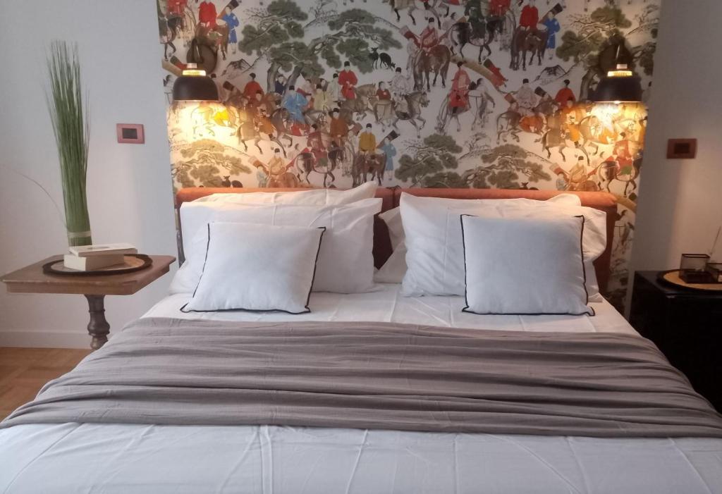 瓦瑞諾博吉的住宿－Il Nido Segreto b&b-Villa Varinelli，一张带白色枕头的床和墙上的绘画