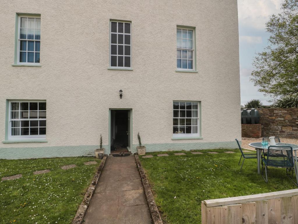 a white house with a table and a table and a patio at Buckland House Annex in Taunton