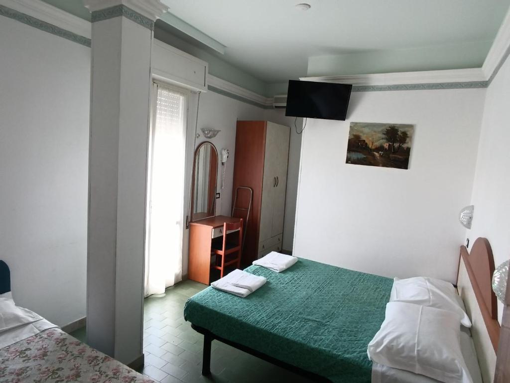 een kleine slaapkamer met een groen bed en een spiegel bij HOTEL AUGUSTUS in Gatteo a Mare