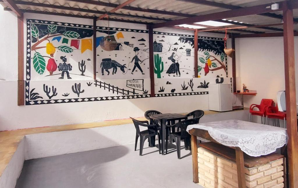 a room with a table and chairs and a mural at Pousada Mandakaru in Maragogi