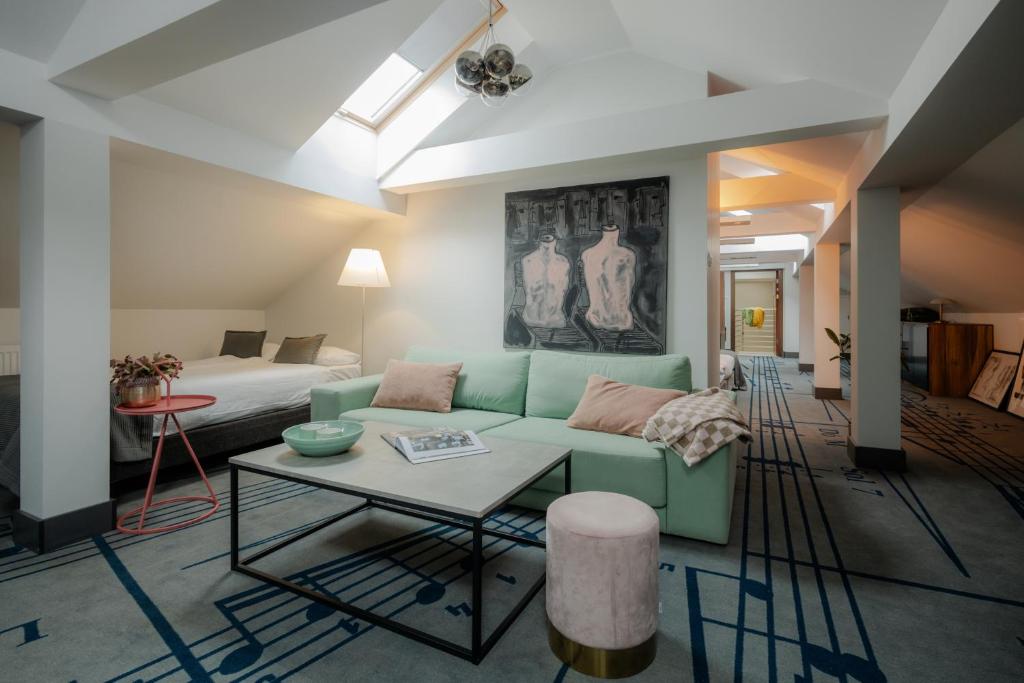 ein Wohnzimmer mit einem grünen Sofa und einem Bett in der Unterkunft Hotel Beethoven in Danzig