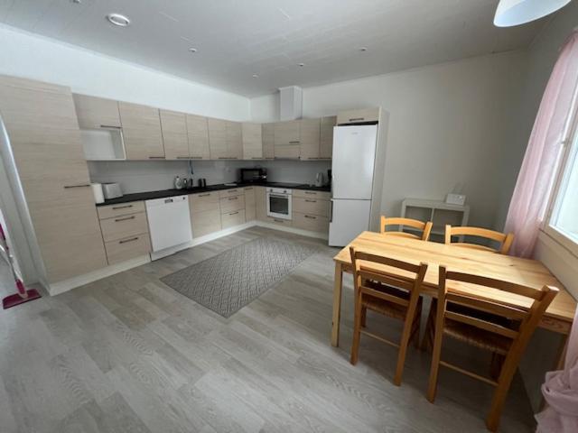 a kitchen with a table and chairs and a refrigerator at Apartment Kuokkamaantie, Pyhäjoki in Pyhäjoki