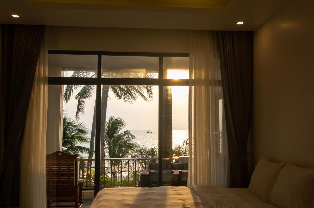 Sealight Villa and House Phu Quoc في فو كووك: غرفة نوم مع نافذة كبيرة مطلة على المحيط