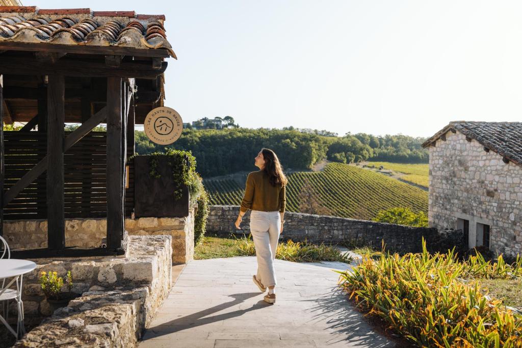 a woman walking down a walkway near a vineyard at Les Hauts de Broze in Broze