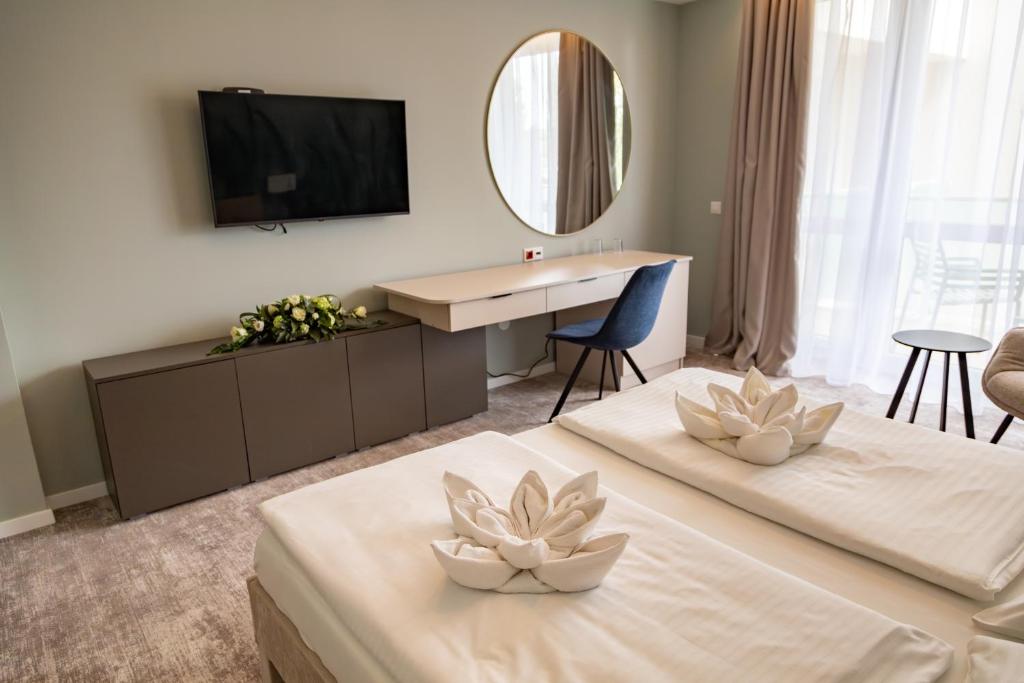 um quarto de hotel com duas camas e uma televisão em Hotel Atlantis Medical, Wellness & Conference em Hajdúszoboszló